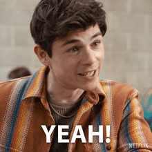 a man wearing a plaid shirt is smiling and says yeah