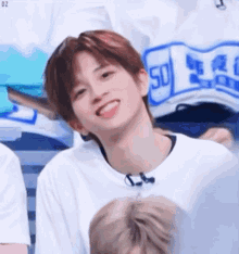 a young man is smiling and sticking his tongue out while wearing a white t-shirt .