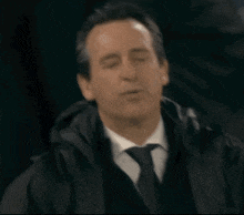 a man in a suit and tie is wearing a hooded jacket