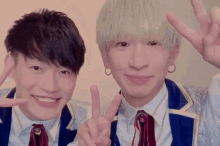 two young men are giving a peace sign and smiling for the camera