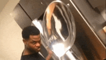 a man is standing in front of a washing machine and looking at the reflection of himself in the mirror .