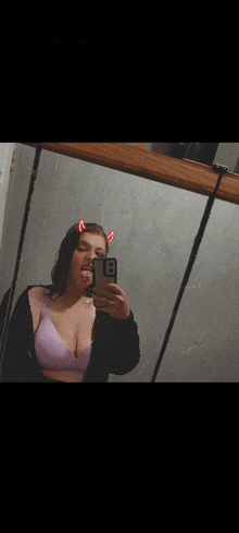 a woman taking a selfie in front of a mirror with devil horns on her hair