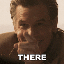 a man in a suit is pointing at the camera with the word there above him