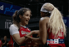 two female basketball players from the washington wizards hugging each other