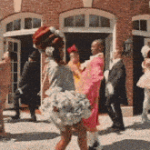 a woman in a pink dress is dancing in front of a group of people