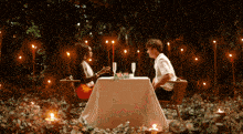 a man and a woman are sitting at a table with candles