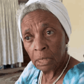 an elderly woman wearing pearls and a white headband