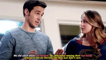 a man and a woman are standing next to each other and the woman is wearing a superman sweater .