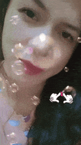 a close up of a woman blowing soap bubbles with a cartoon hand on the bottom right