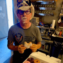 a man wearing a martial & movement arts studio shirt holds a donut in his hands