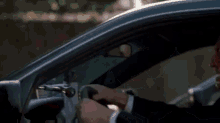 a man is driving a car and laughing while holding the steering wheel .