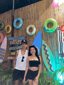 a man and a woman are standing in front of a sign that says welcome to my party