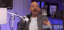 a man is laughing in front of a microphone and the words dark web are visible