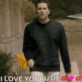 a man in a black sweater is walking down a street and says i love you cutie