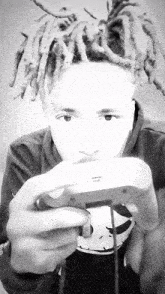 a young man with dreadlocks is holding a video game controller in his hand .