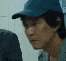 a man wearing a blue hat is looking at another man .