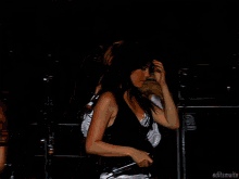 a woman singing into a microphone in front of a yamaha amplifier