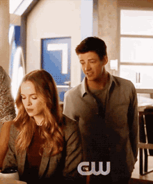 a man and a woman are standing next to each other with a cw logo in the corner