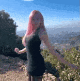 a woman with pink hair is wearing a black dress and standing on top of a hill .