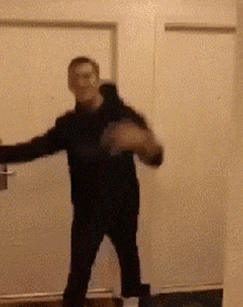 a man in a black sweater is standing in front of a door