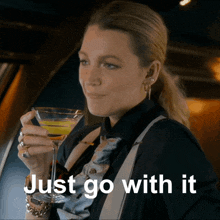 a woman is holding a martini glass with the words just go with it written below her