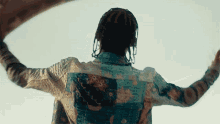 a man with dreadlocks is standing in front of a blue sky