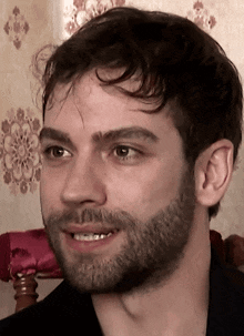 a man with a beard and a black shirt smiles
