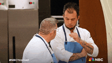 two men are talking in a kitchen with the nbc logo visible