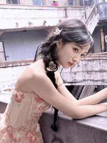 a woman in a pink dress is leaning against a railing
