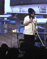 a woman is standing in front of a microphone holding a broom