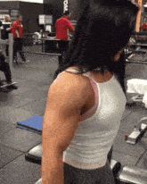 a woman is lifting weights in a gym with the word gym on the wall