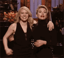 a couple of women are posing for a picture and one of them has her arm around the other 's shoulder