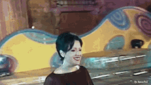 a woman is smiling and standing in front of a colorful wall .
