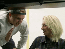 a man wearing a hat and glasses talks to another man
