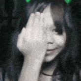 a girl with long hair is covering her eyes with her hand .