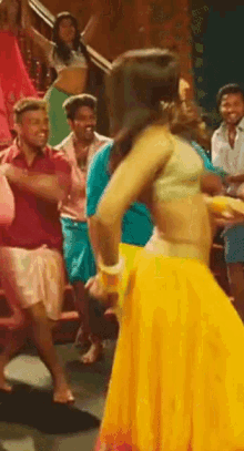 a woman in a yellow skirt is dancing in front of a group of people