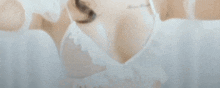 a woman in a white dress is laying on a bed and looking at the camera .