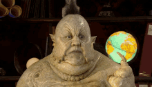 a statue of a man with a mohawk is holding a globe in his hand