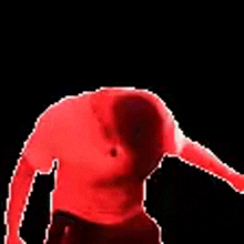 a man with a mohawk is dancing in a red shirt and black shorts .