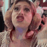 a woman with red hair is making a funny face while standing in front of a crowd .