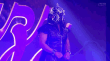a wrestler in a mask flexes his muscles in front of a purple background with the letters fite on it