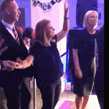 a group of people are dancing at a party and one woman is giving a high five .