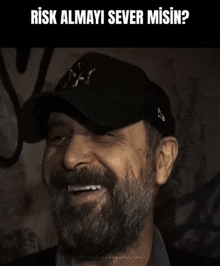 a man with a beard wearing a black hat is smiling