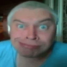 a man wearing headphones and a blue shirt is making a funny face