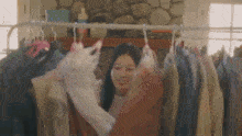 a woman is standing in front of a rack of clothes and holding a sweater .