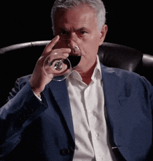 a man in a suit is holding a glass of wine