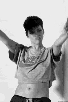 a black and white photo of a woman wearing a nike crop top and a chain around her neck .