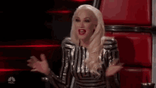 a woman is sitting in a chair with her arms outstretched and talking .