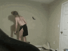 a man in black shorts is standing in a room with a hole in the wall