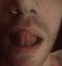 a close up of a man 's mouth and nose with his tongue sticking out .